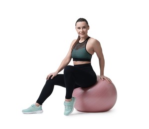 Smiling woman in sportswear sitting on fitness ball against white background