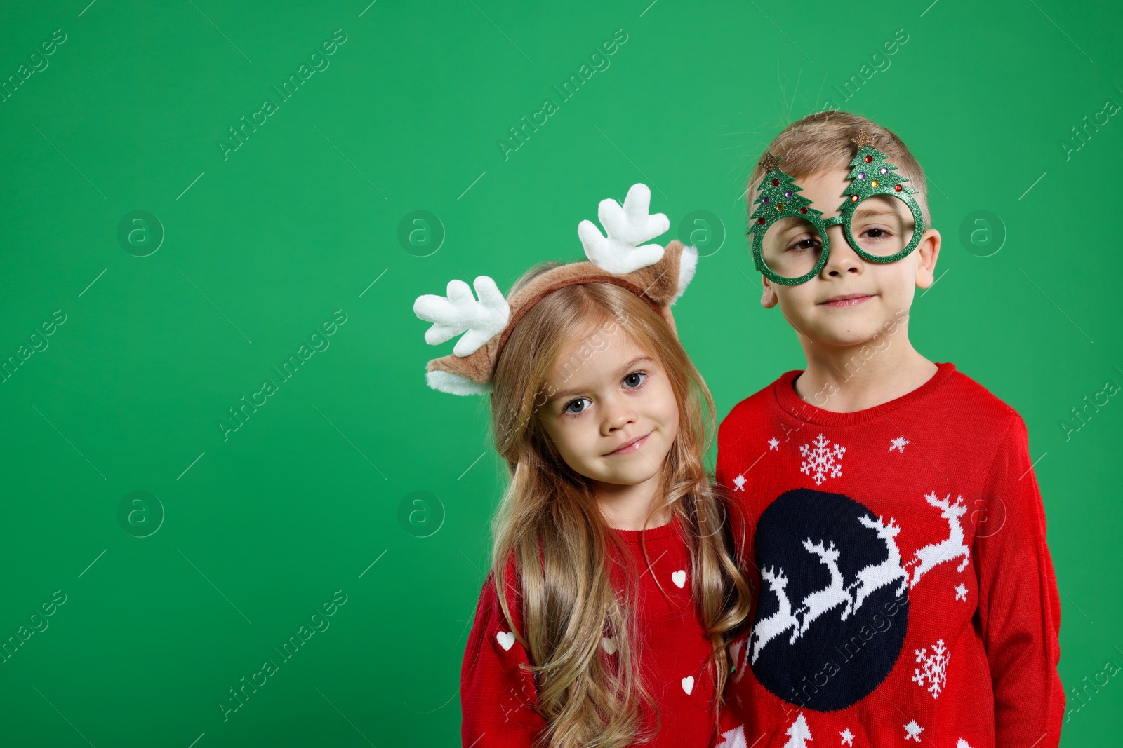 Photo of Cute little children in Christmas sweaters and accessories on green background. Space for text