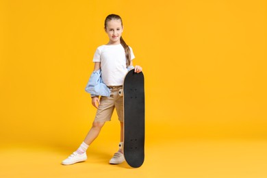 Photo of Stylish girl with skateboard on yellow background