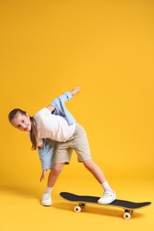 Photo of Stylish girl with skateboard on yellow background