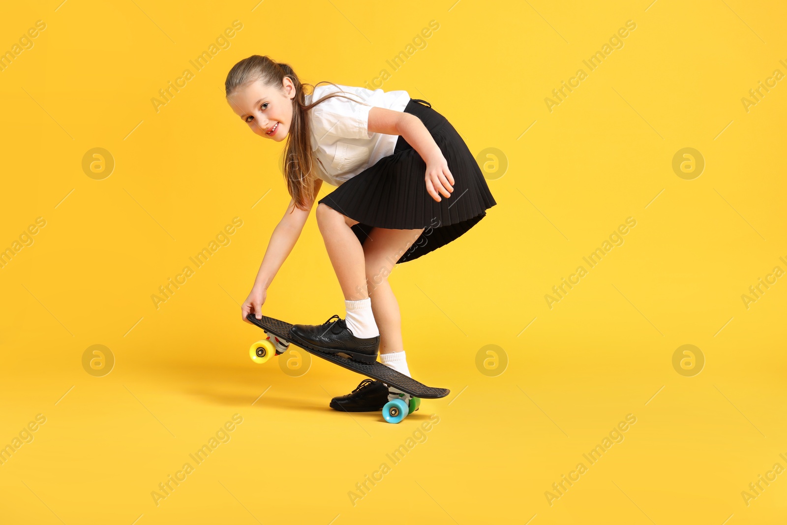 Photo of Little girl with penny board on yellow background