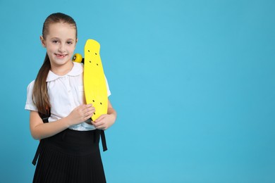 Photo of Little girl with penny board on light blue background, space for text