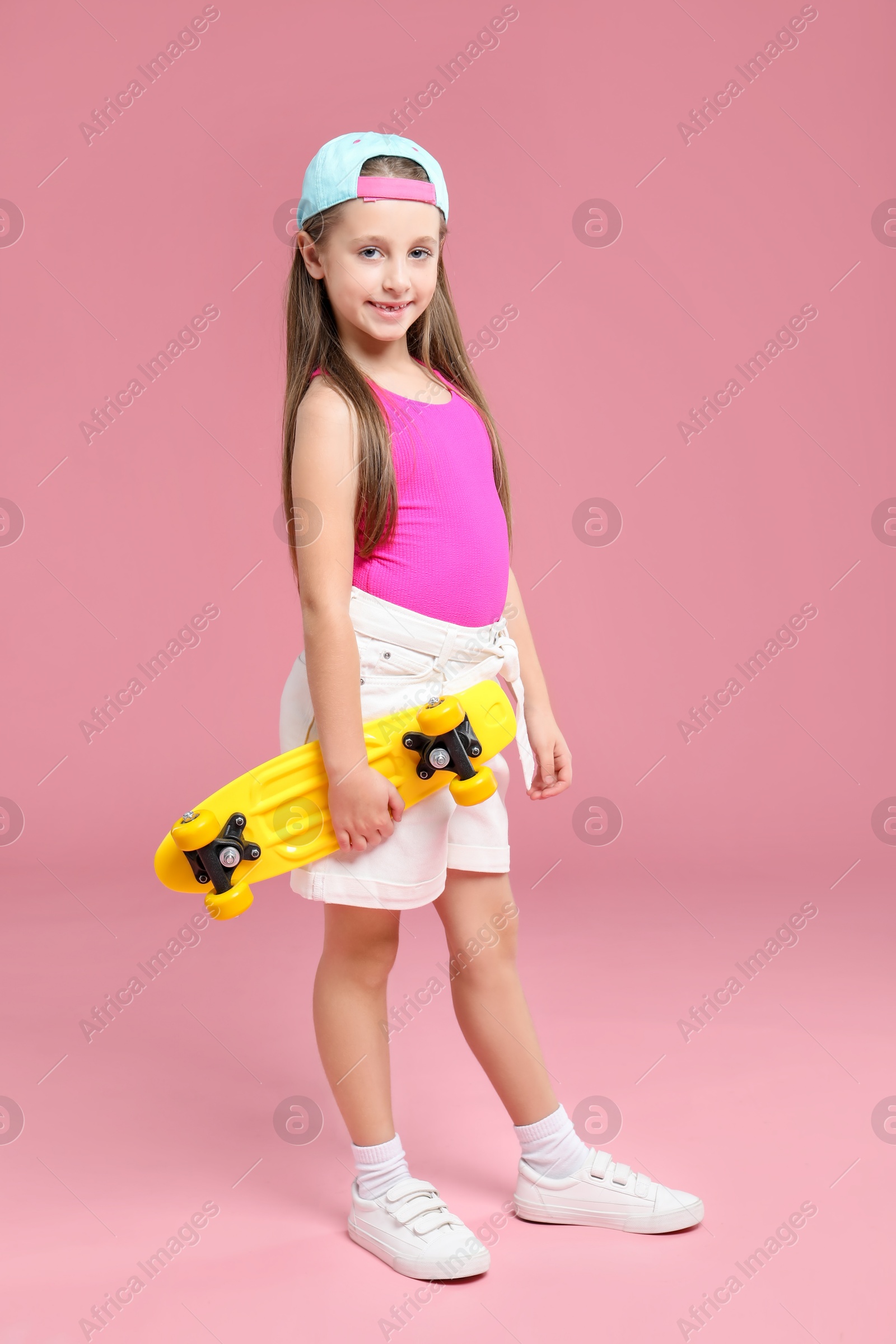 Photo of Little girl with penny board on pink background