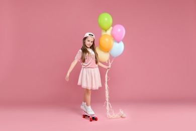 Photo of Little girl with colorful balloons standing on penny board against pink background