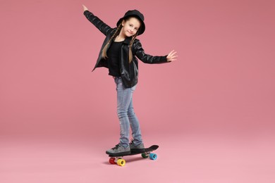 Photo of Little girl standing on penny board against pink background