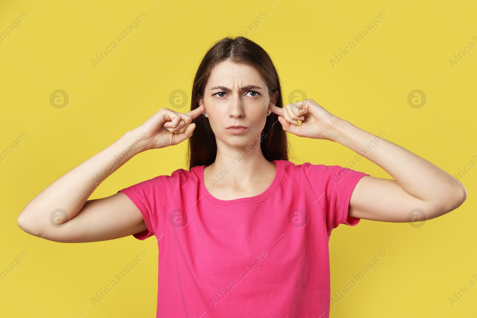 Photo of Woman covering her ears with fingers on dark yellow background