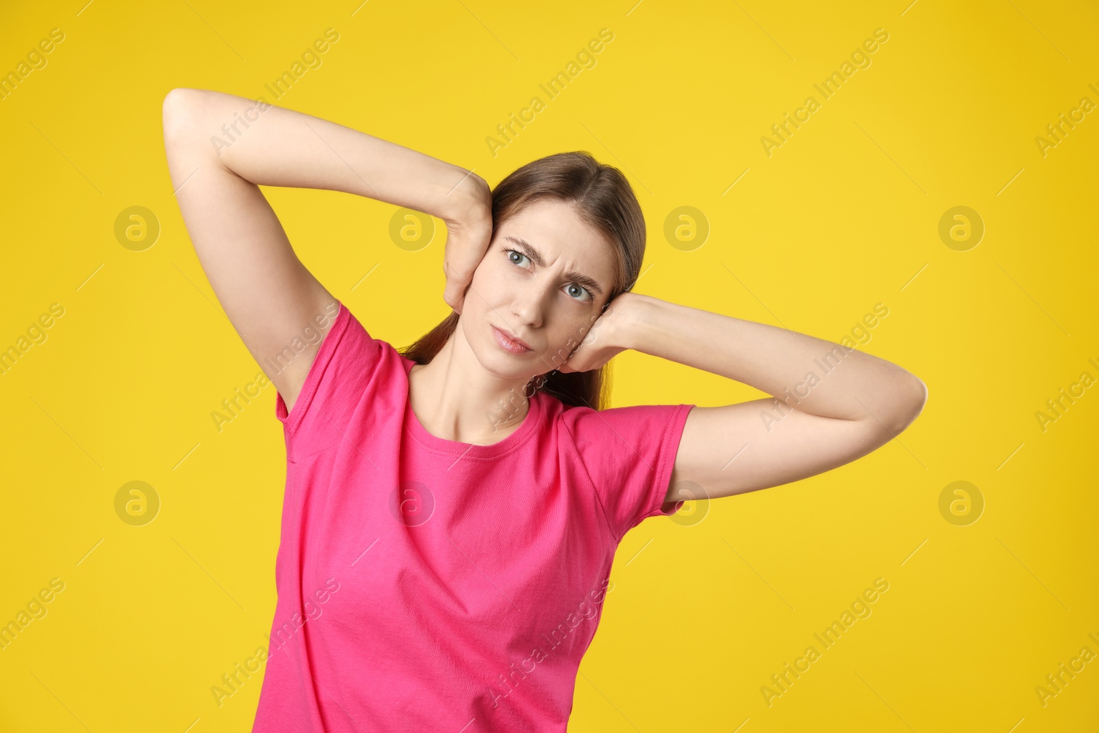 Photo of Woman covering her ears on dark yellow background