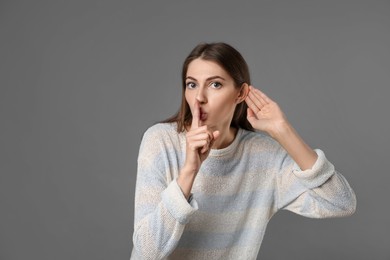 Photo of Woman showing hand to ear gesture on grey background, space for text