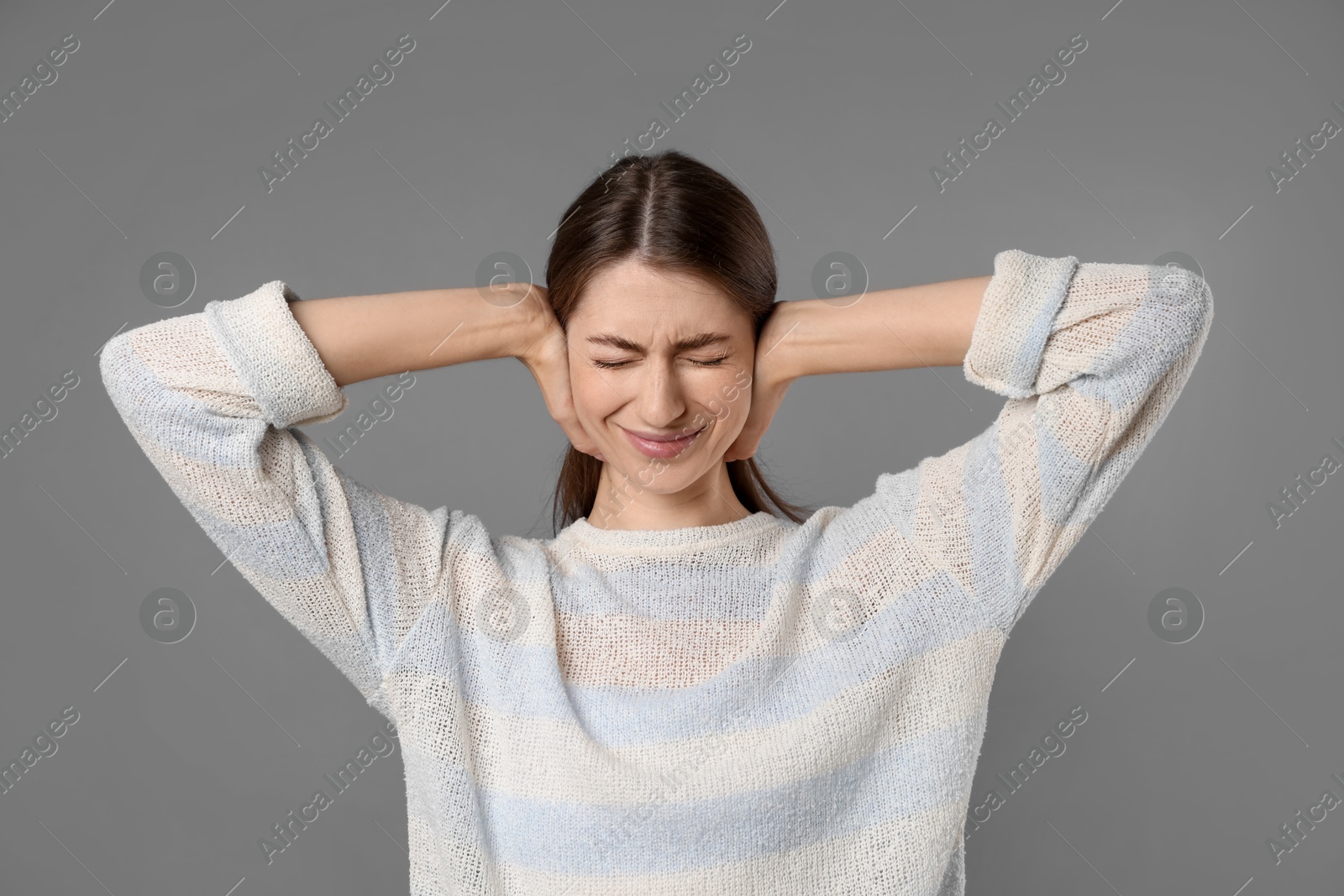 Photo of Woman covering her ears on grey background