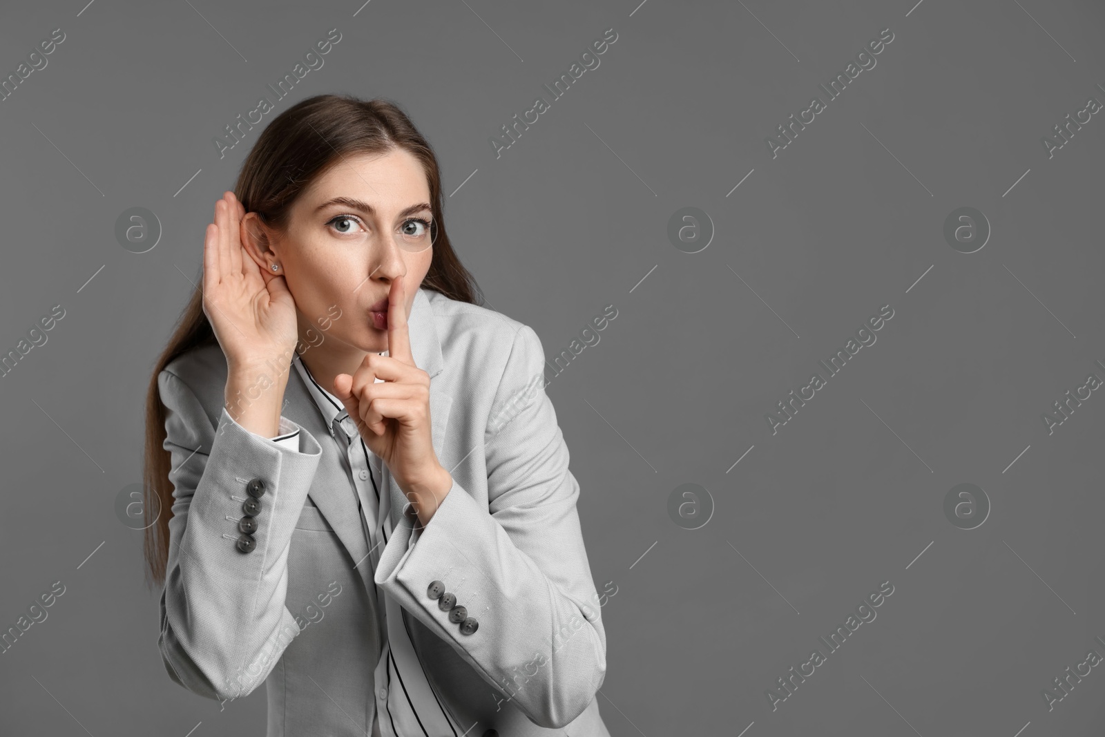 Photo of Woman showing hand to ear gesture on grey background, space for text