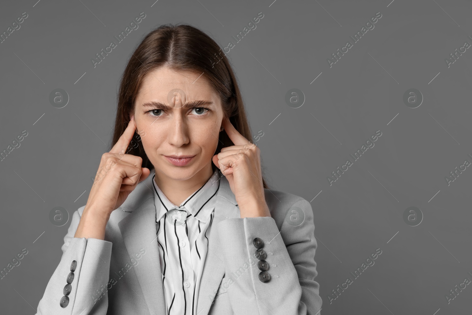 Photo of Woman covering her ears with fingers on grey background