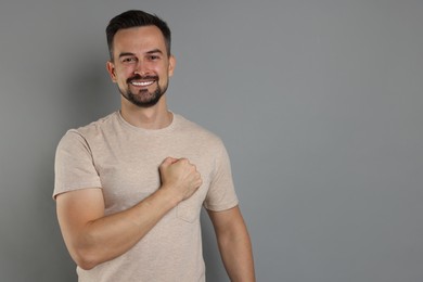 Photo of Man making promise on grey background, space for text. Oath gesture