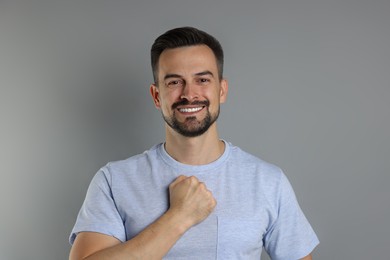 Photo of Man making promise on grey background. Oath gesture