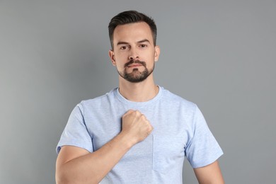 Photo of Man making promise on grey background. Oath gesture