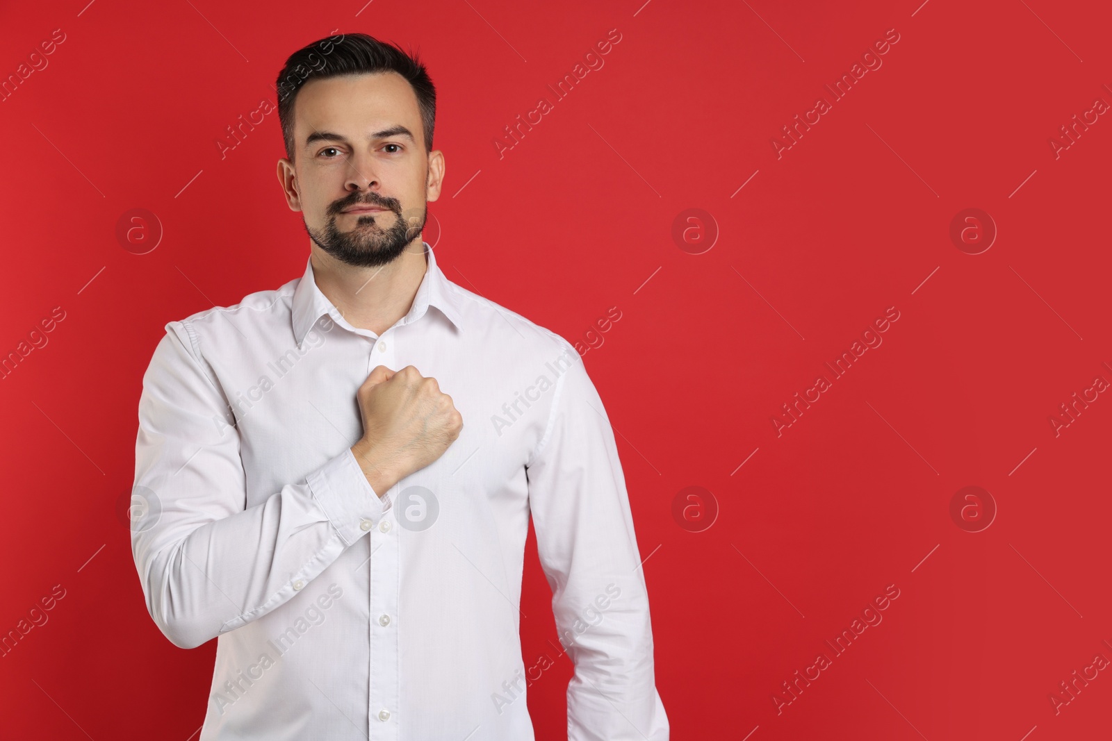 Photo of Man making promise on red background, space for text. Oath gesture