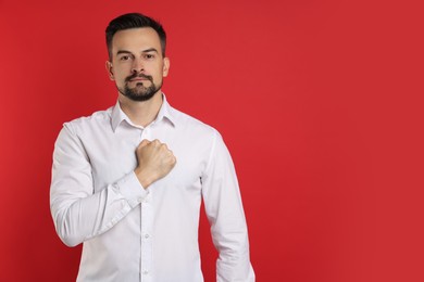 Photo of Man making promise on red background, space for text. Oath gesture