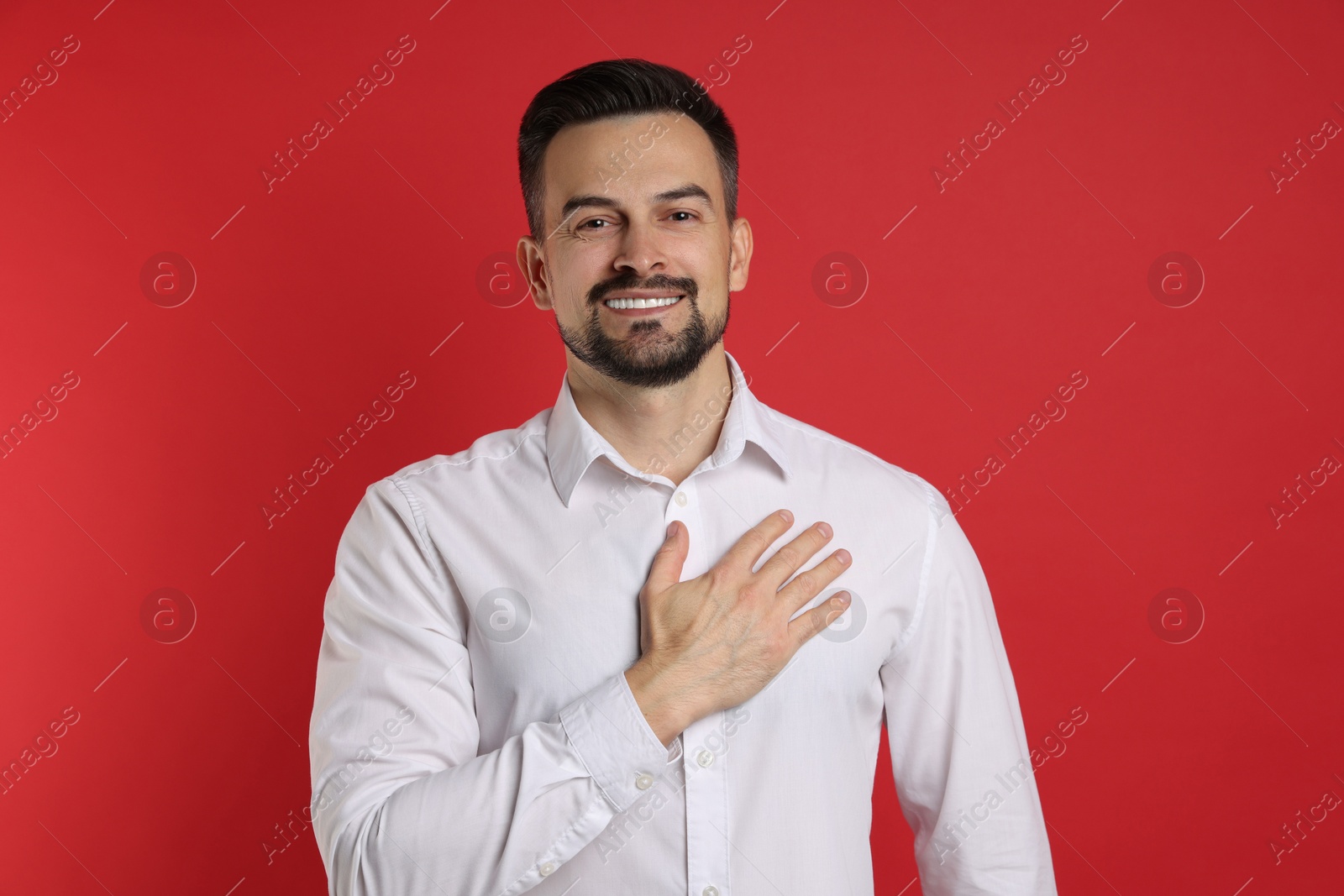 Photo of Man making promise on red background. Oath gesture