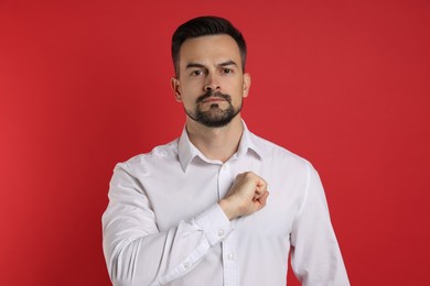 Photo of Man making promise on red background. Oath gesture