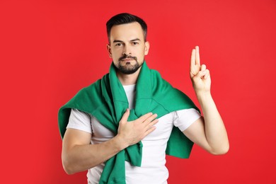 Photo of Man showing oath gesture on red background. Making promise