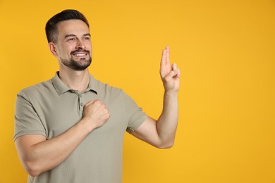 Photo of Man showing oath gesture on orange background, space for text. Making promise