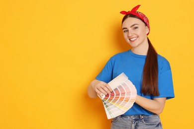 Photo of Portrait of young decorator with color palettes on orange background, space for text