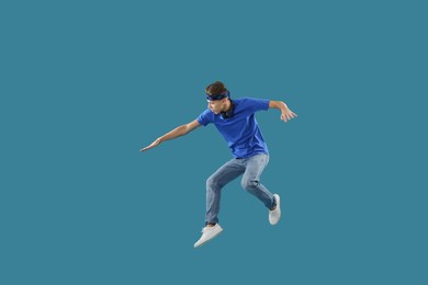 Photo of Handsome skater jumping on light blue background