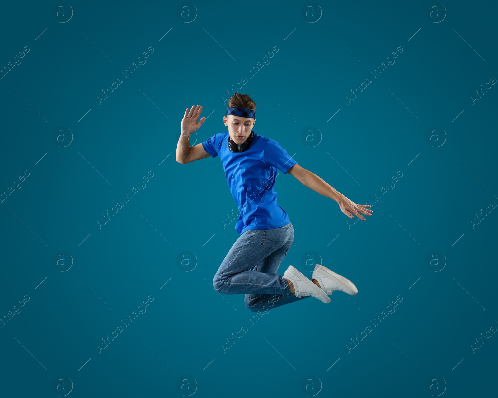 Photo of Handsome skater jumping on light blue background