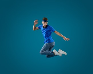 Photo of Handsome skater jumping on light blue background