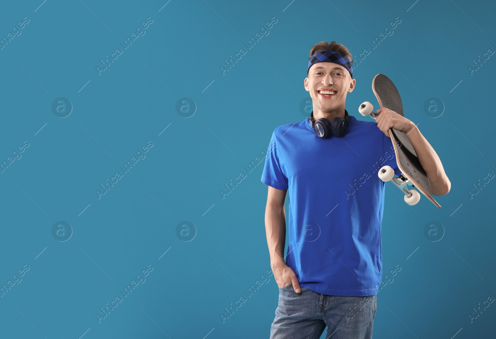 Photo of Happy man with skateboard on light blue background. Space for text