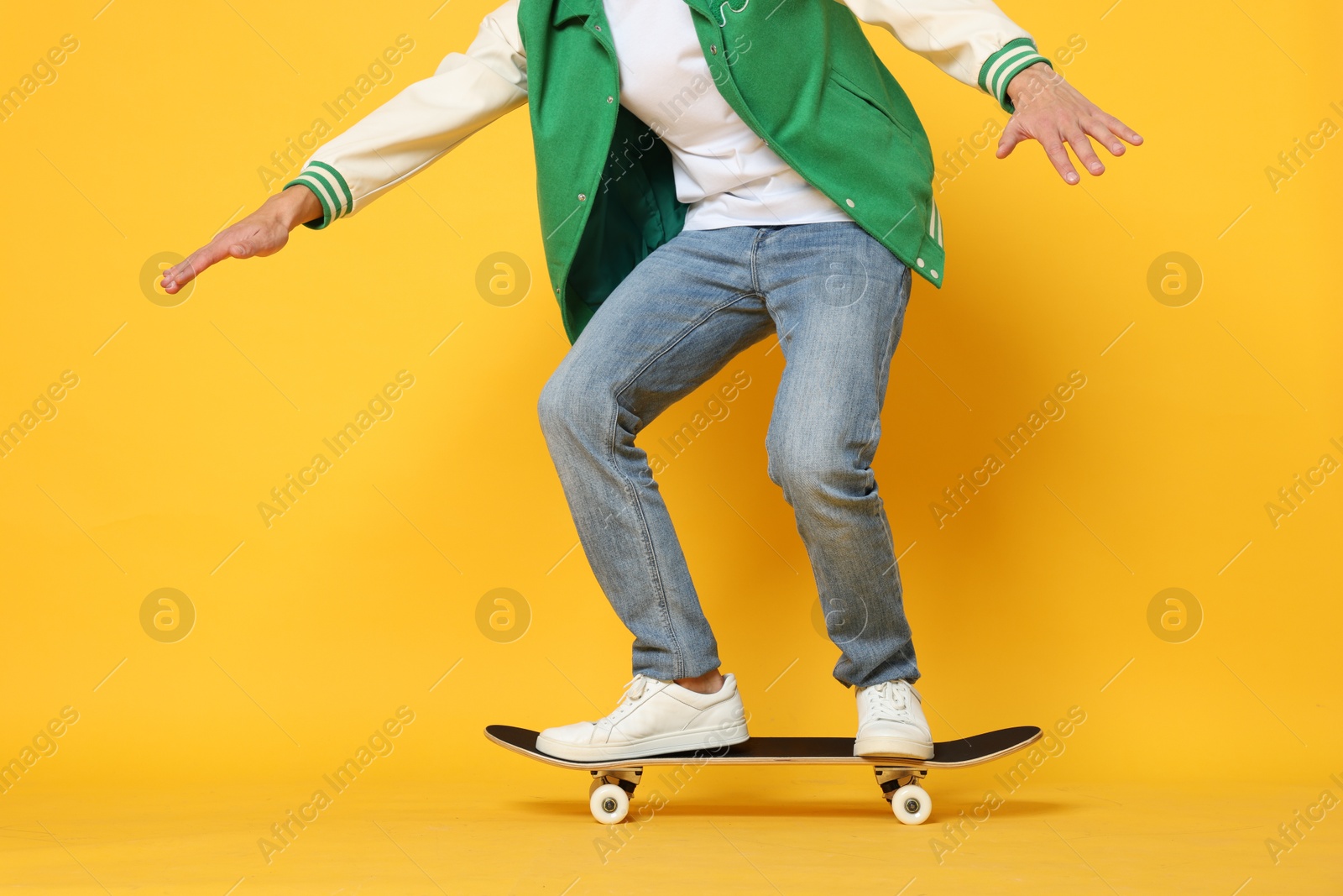 Photo of Man riding skateboard on orange background, closeup