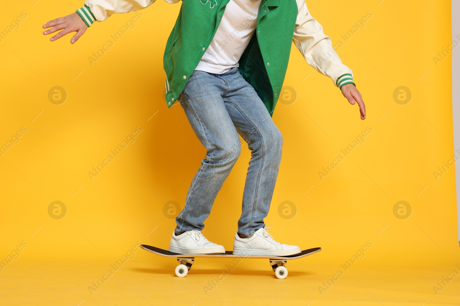 Photo of Man riding skateboard on orange background, closeup