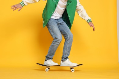 Man riding skateboard on orange background, closeup