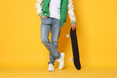 Photo of Man with skateboard on orange background, closeup