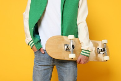 Photo of Man with skateboard on orange background, closeup