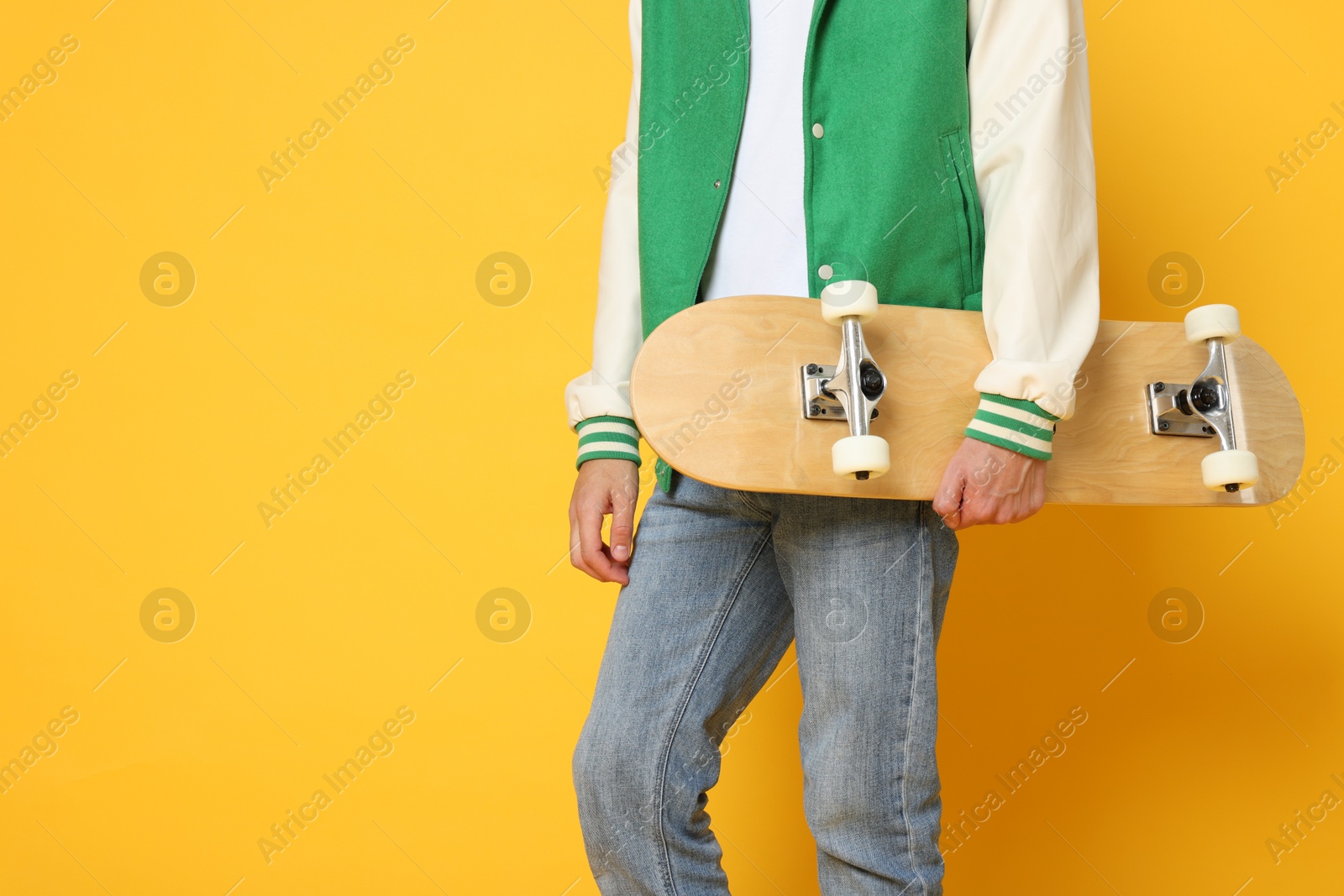 Photo of Man with skateboard on orange background, closeup. Space for text