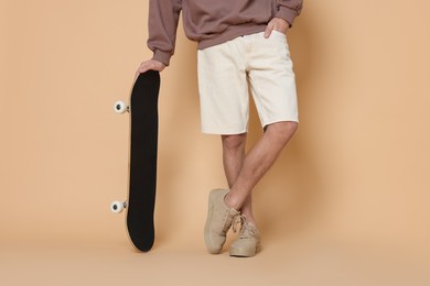 Photo of Man with skateboard on beige background, closeup