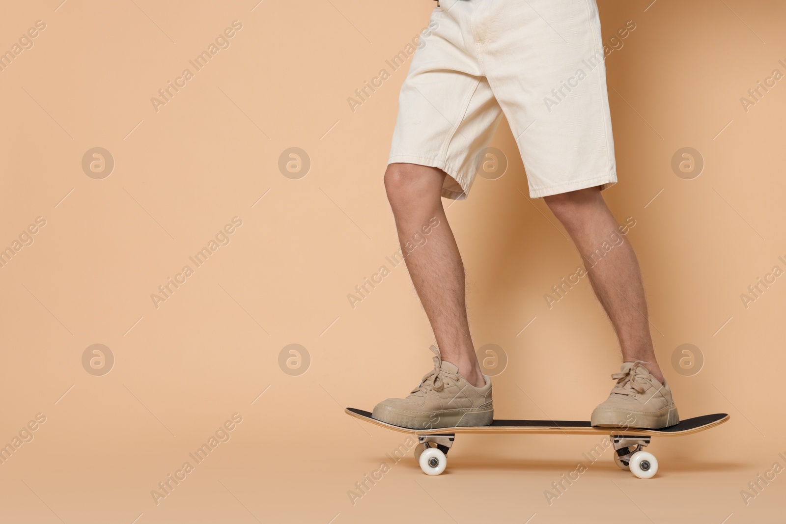 Photo of Man riding skateboard on beige background, closeup. Space for text