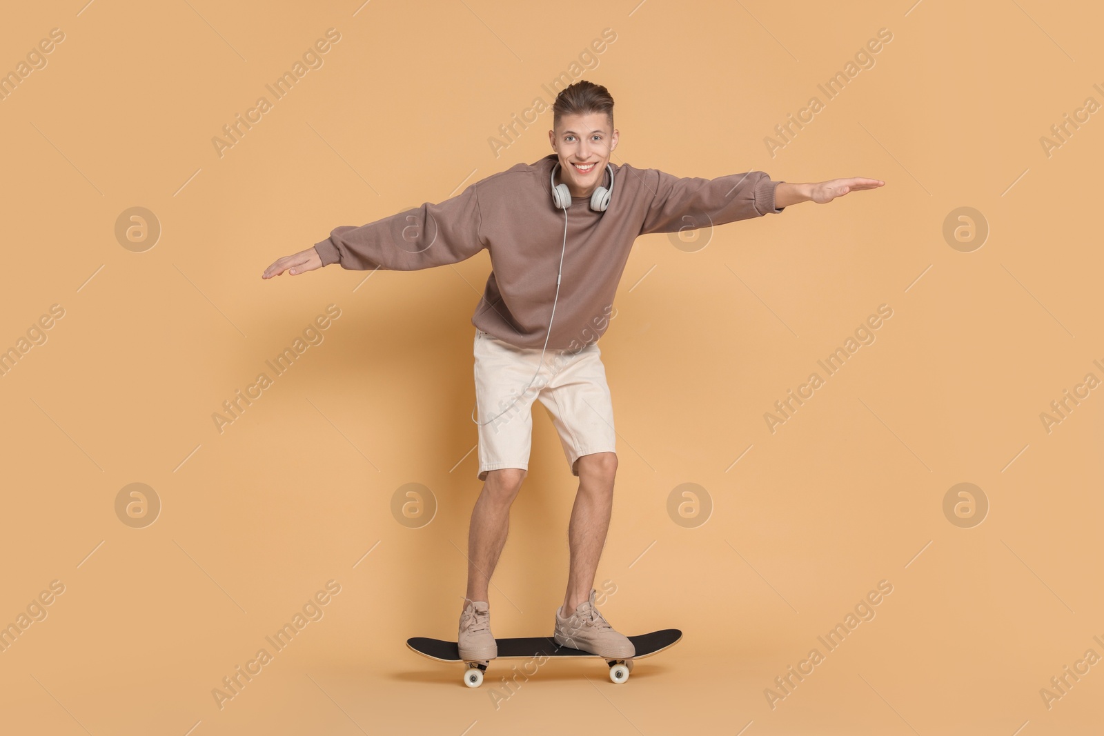 Photo of Happy man riding skateboard on beige background