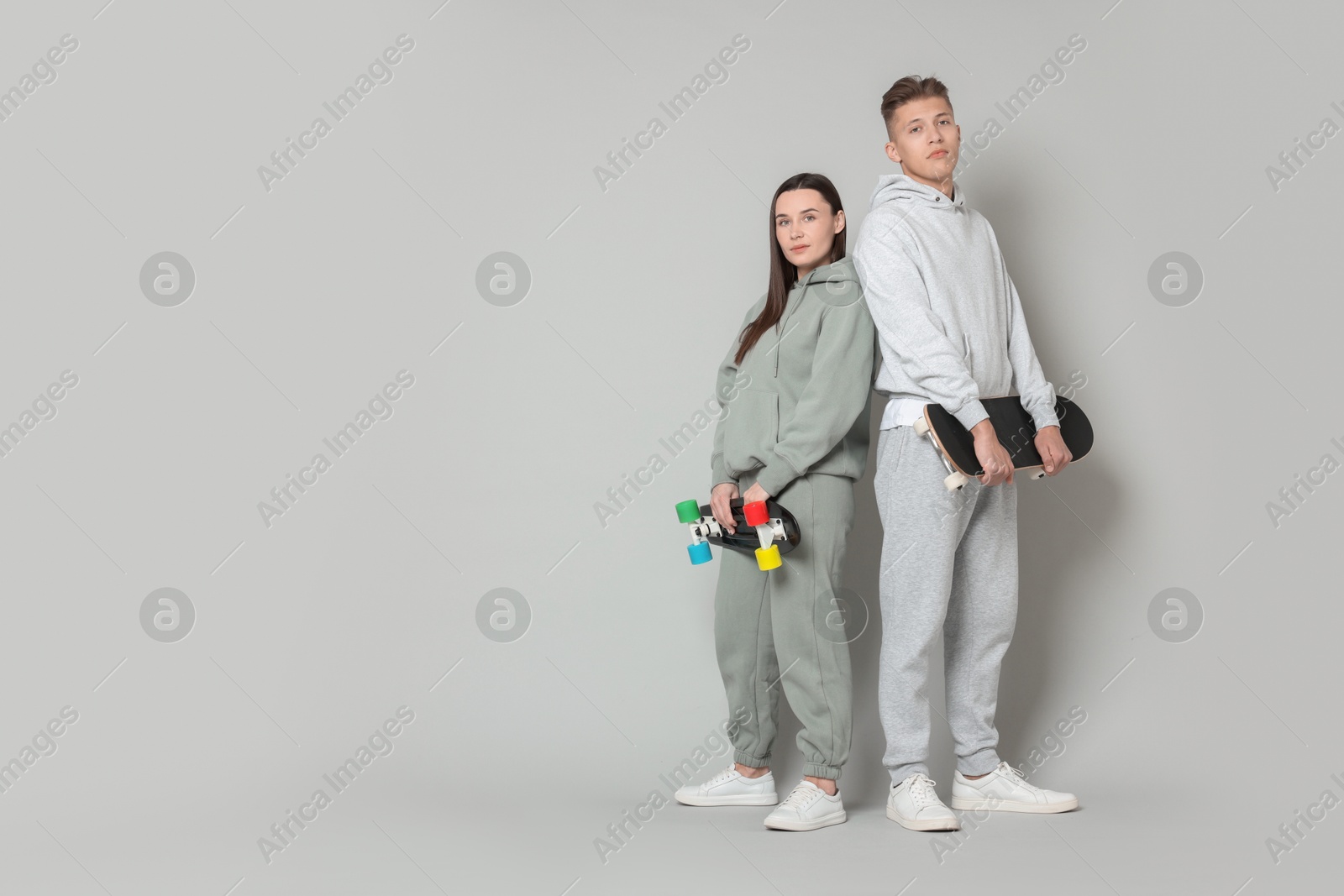 Photo of Friends with skateboards on light grey background. Space for text