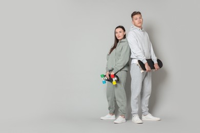 Photo of Friends with skateboards on light grey background. Space for text