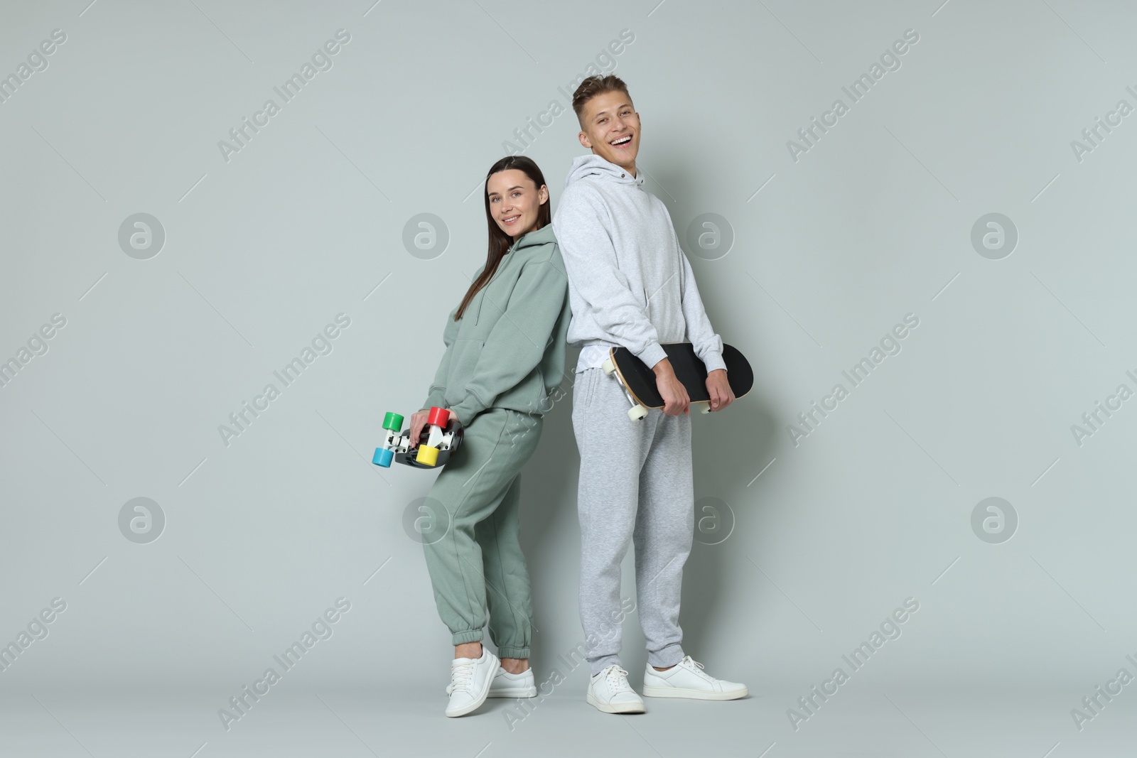 Photo of Happy friends with skateboards on light grey background