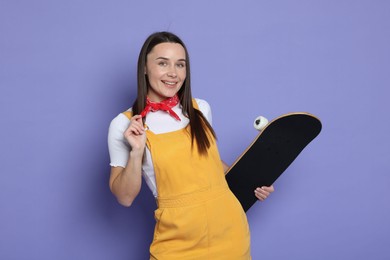 Photo of Smiling woman with skateboard on violet background