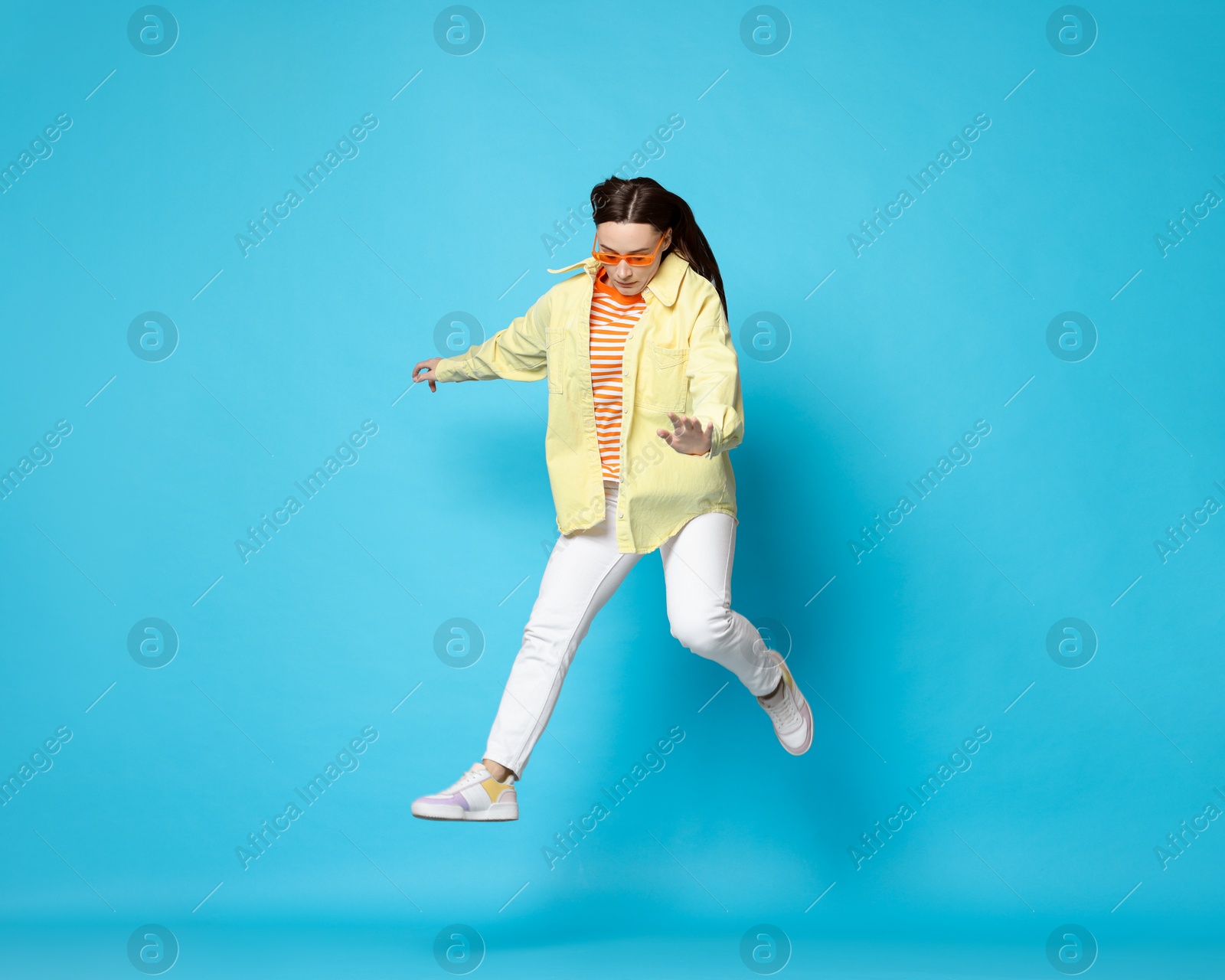 Photo of Beautiful female skater jumping on light blue background