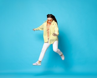 Photo of Beautiful female skater jumping on light blue background