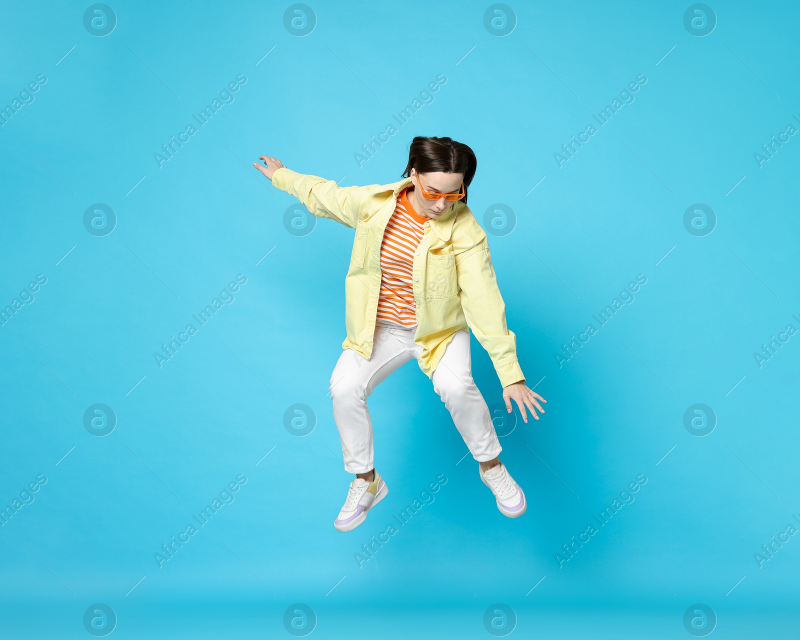 Photo of Beautiful female skater jumping on light blue background