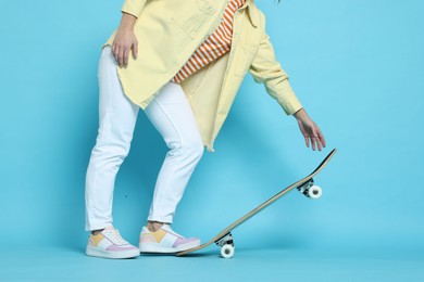 Photo of Woman with skateboard on light blue background, closeup