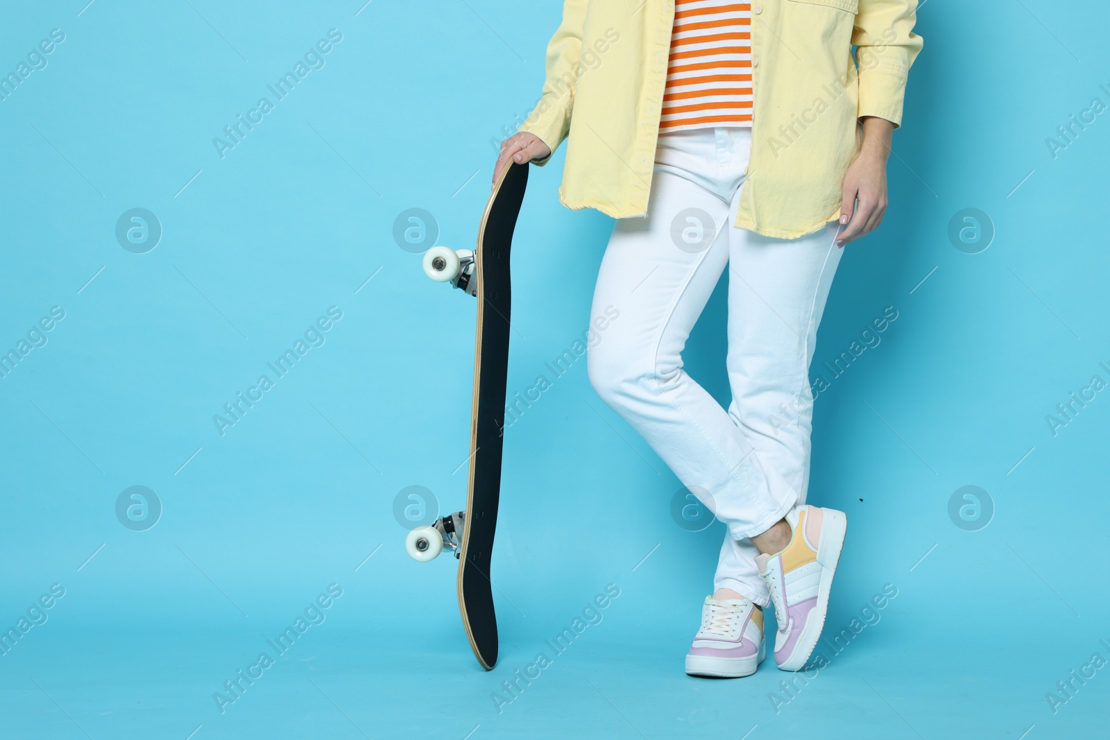 Photo of Woman with skateboard on light blue background, closeup. Space for text