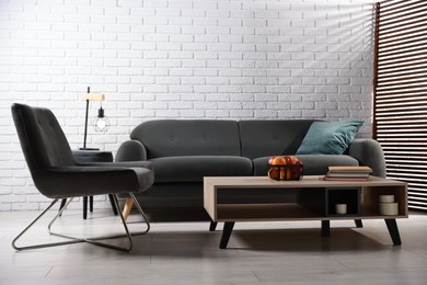 Photo of Comfortable sofa, armchair and coffee table in living room. Interior design