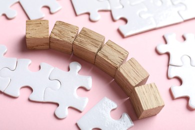 Photo of Wooden cubes and puzzle pieces on pink background, closeup