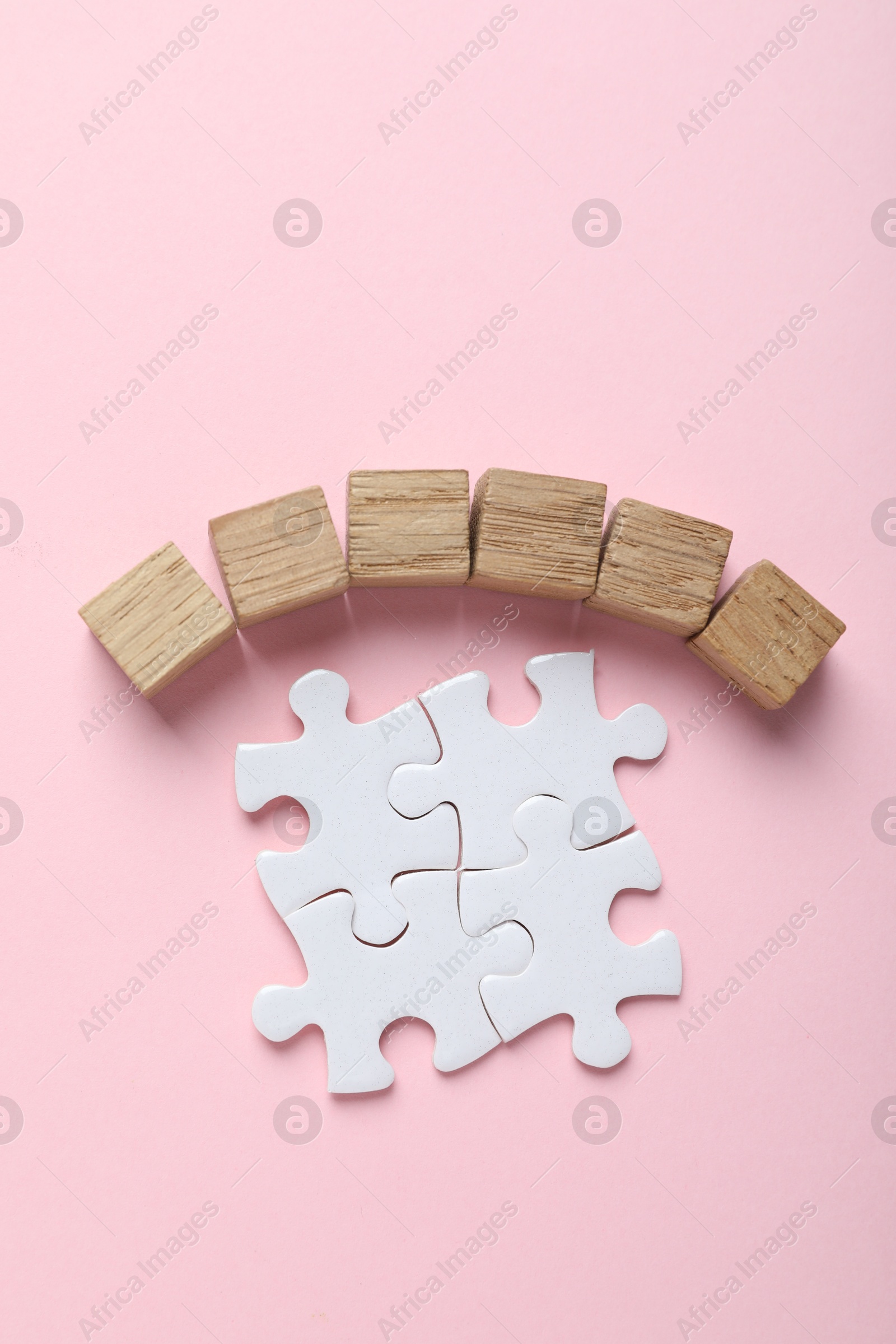 Photo of Wooden cubes and puzzle pieces on pink background, flat lay